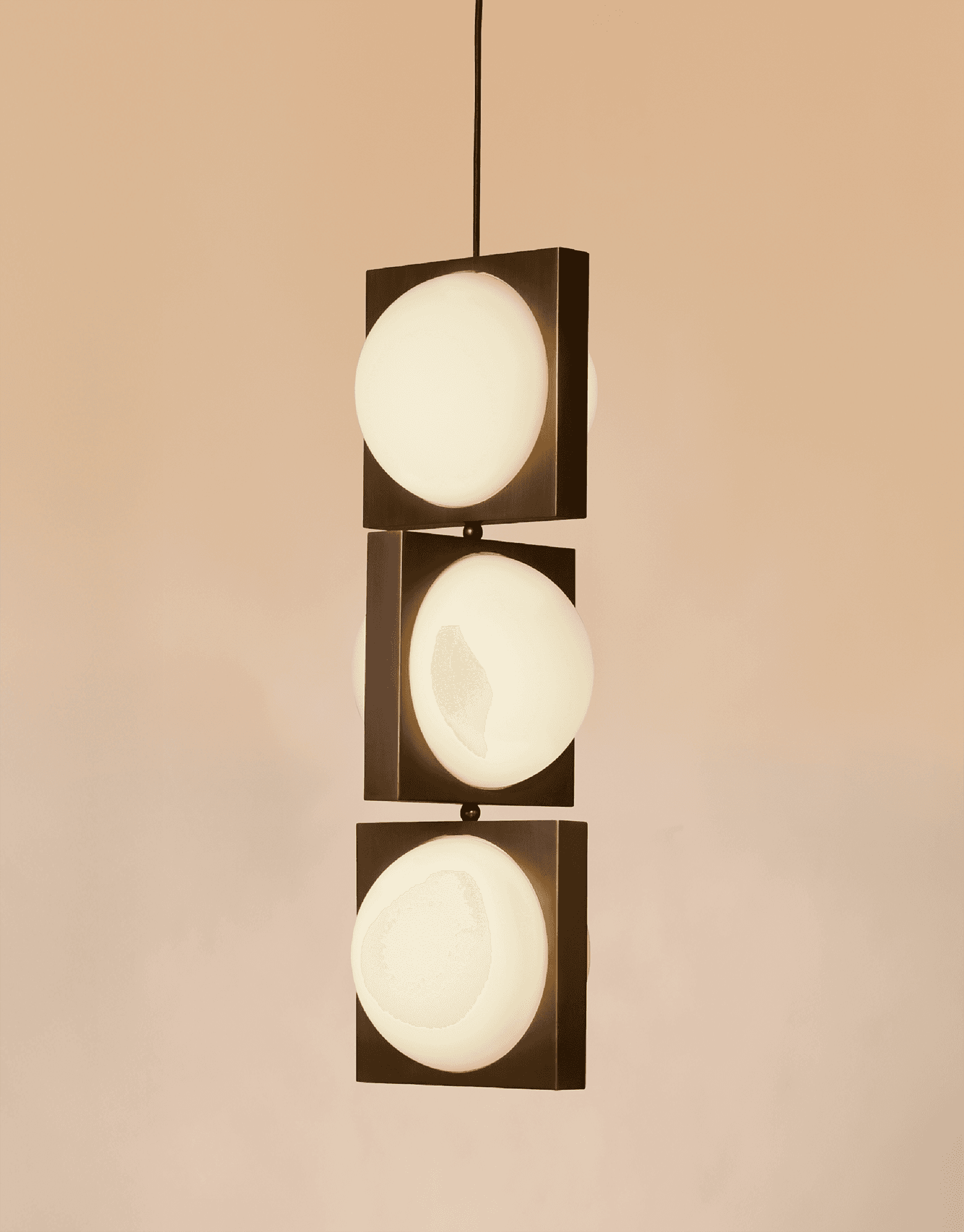 A pendant with three circular lights set in mod squares of black brass.