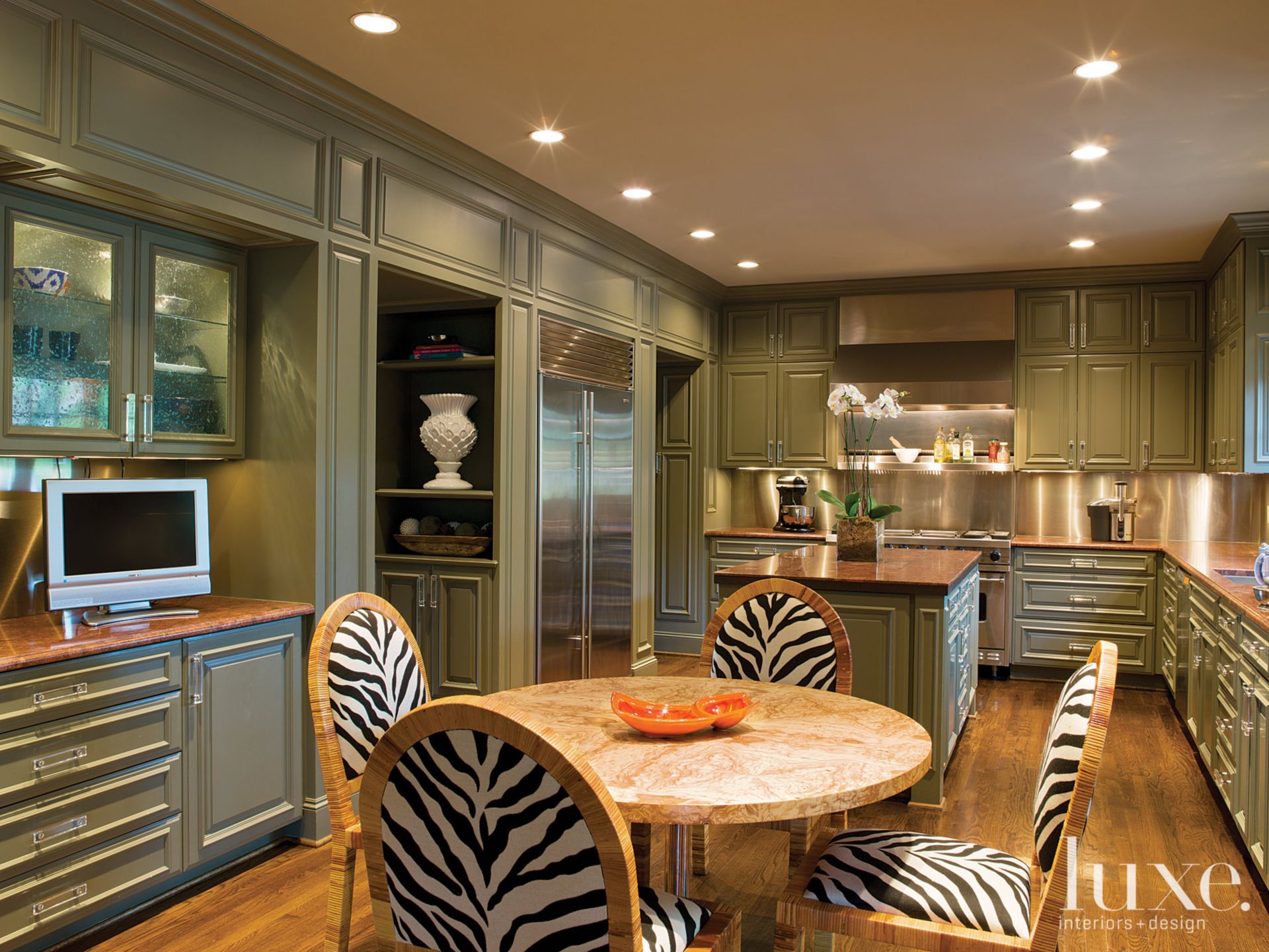 kitchen with green cabinets, wooden dining table and zebra patterned chairs