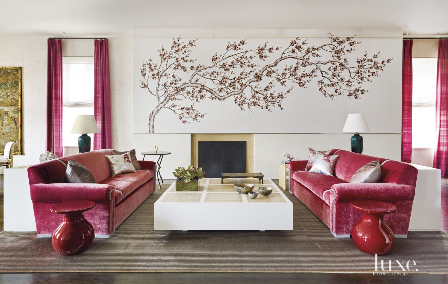 living room with pink velvet couches, white table and pink tree art