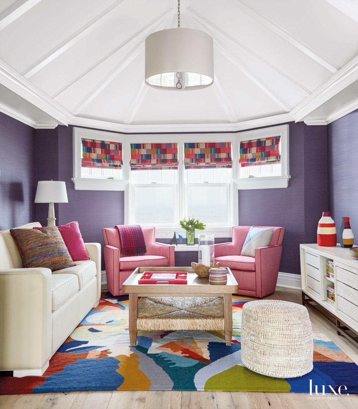 purple bedroom with pink armchairs and white furnishings