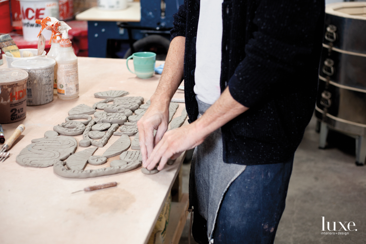 William O’Brien’s hands putting patterns into clay on wood table