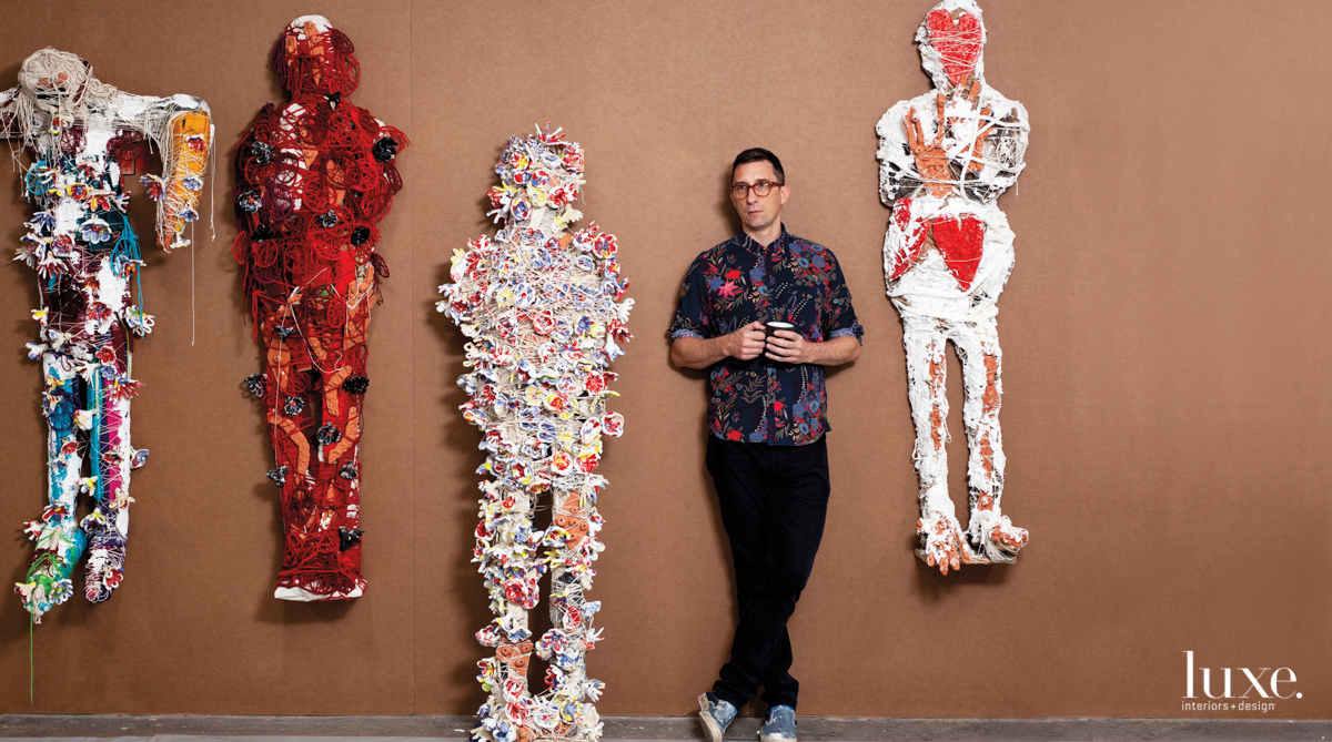 William J. O'Brien in front of brown wall and three of his mixed-media works