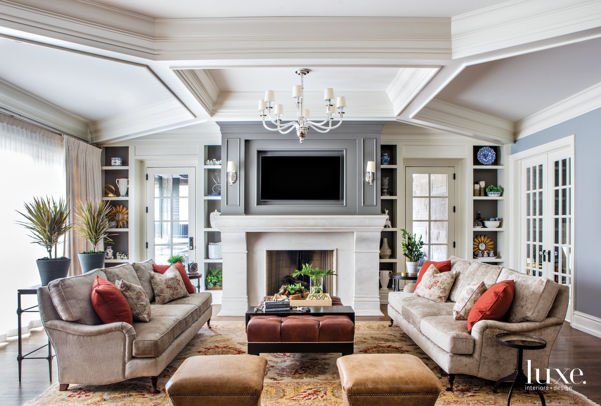 spacious white living room with tan sofas, ottomans and white fireplace by Designstorms