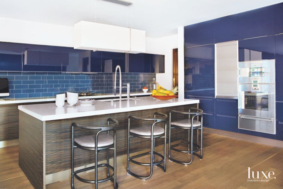 spacious kitchen with blue backsplash and walls with white cabinetry