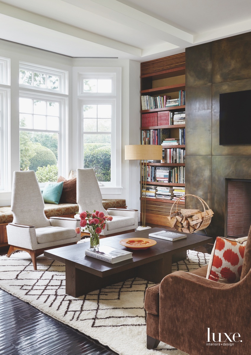 modern living room with white accent chairs, organic wood coffee table and brown fireplace