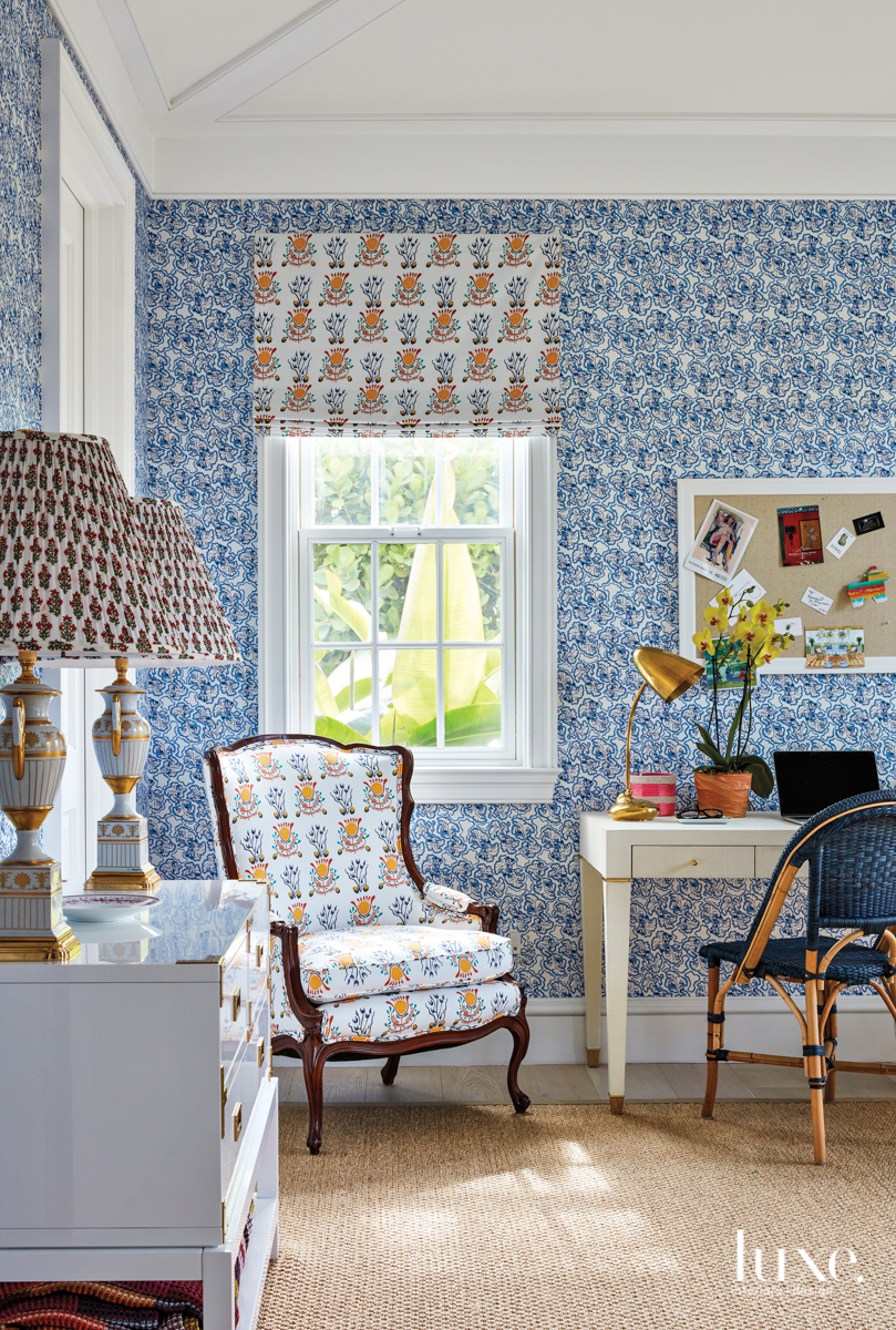 The wife's office shows off Skok's Brimfield wallpaper in Delft Blue from Monica James; her Emmie fabric in the Multi colorway appears on the valance and antique armchair. Bungalow 5's Tansu console table, holding vintage lamps acquired in London, and Claudette desk counter Serena &amp; Lily's Sunwashed Riviera chair on a Fibreworks rug.