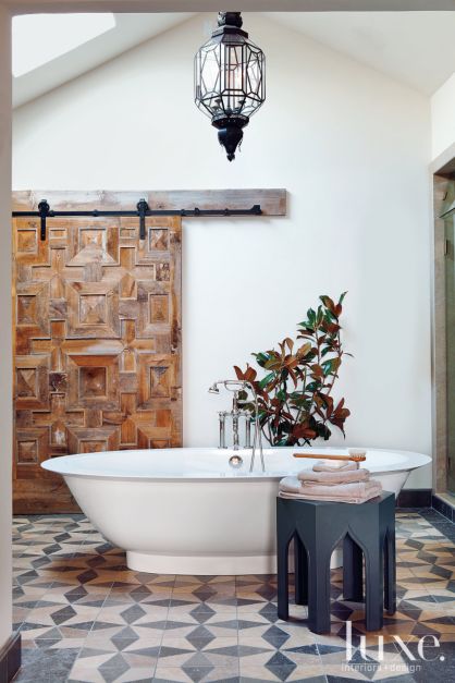 decorative pine plank barn door in bathroom with freestanding white tub 