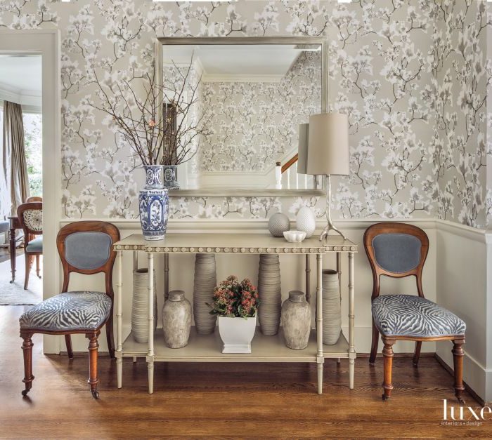 white living area with white floral wallcovering, shelf and two blue chairs