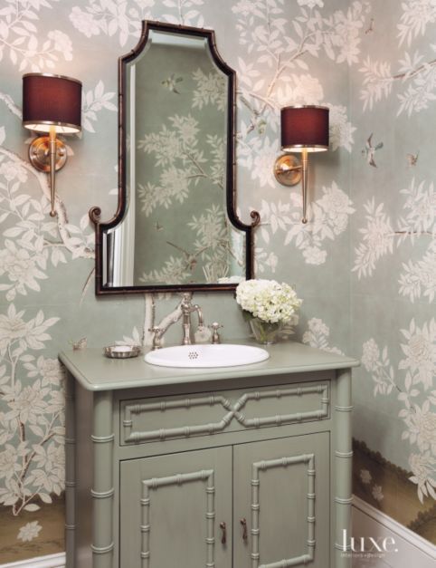 pale green bathroom with arched mirror, green sink and drawer and floral wallpaper