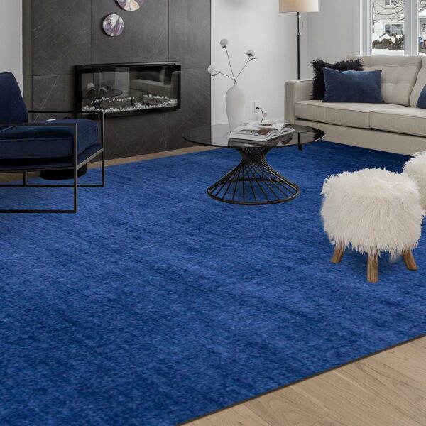 A blue rug complements the white furniture in this living room, adding a touch of color and warmth.