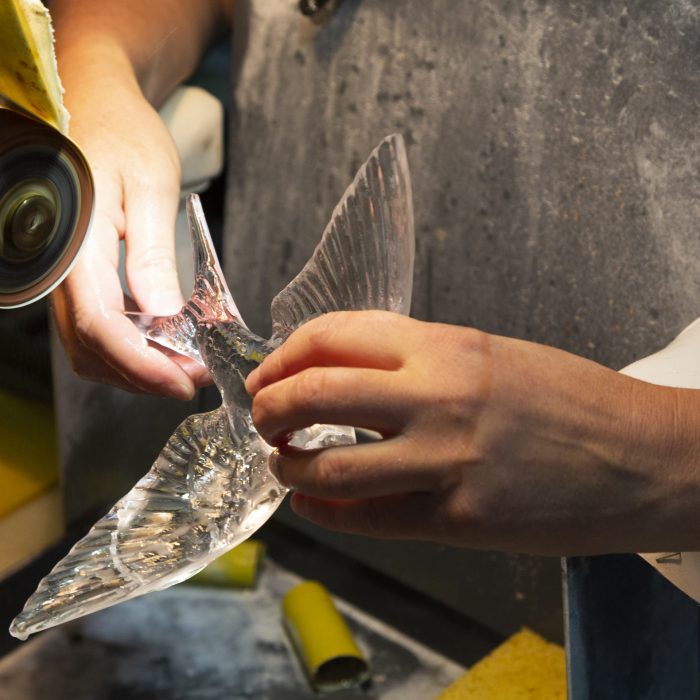 A skilled craftsman perfects a crystal bird.