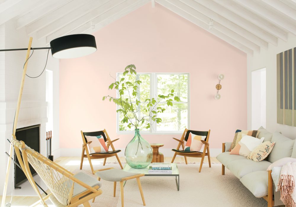 Benjamin Moore's First Light in light-filled living room with white chairs and multicolored cushions