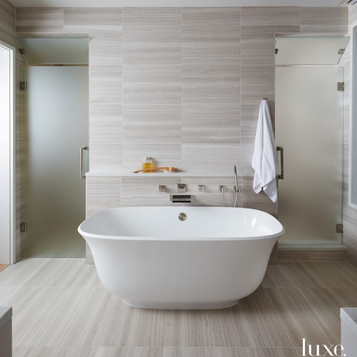 Made of cast ground volcanic limestone and resin, the shapely Amiata tub by Victoria + Albert seems to float amid the honed marble tile from Ann Sacks in the master bath.