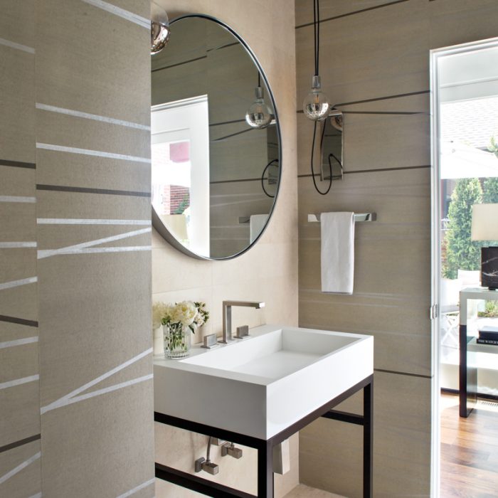 Ann Sacks floor tile and wallcovering by Fromental add interest to the powder room. A Desiron mirror hangs above the vanity and sink with a Gessi faucet. The sconces are by Fuse Lighting.
