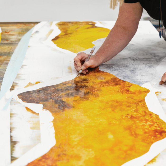 Artist Sarah Winkler adds detail to one of her large-scale paintings.
