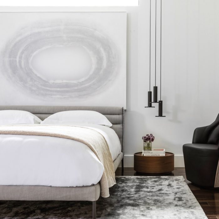 modern minimalist bedroom with modern art, hanging lights above small circular nightstand 