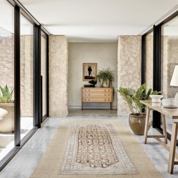 An Arizona Home With Panoramic Vistas Lets Nature Take Center Stage Floor-to-ceiling windows throughout the house maximize the mountain views and strengthen the indoor-outdoor connection. Along the windows in the foyer is a custom table, upon which sits a Gregorius Pineo lamp. An antique rug from David E. Adler leads the way to a Jean de Merry console at the end of the hall.