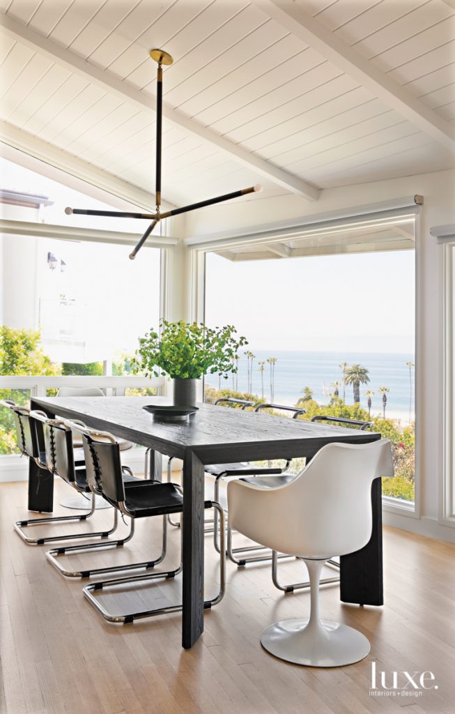 In the dining area, to keep the focus on the view, the designer chose a mix of midcentury forms for the chairs and a clean-lined table from RH. An understated fixture by Apparatus hovers above. Throughout the home, the flooring is by Gaetano Hardwood Floors.
