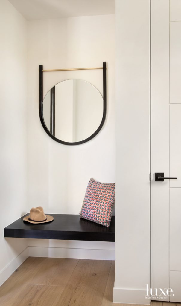 In a vestibule off the entry hall, an oak bench with a black-satin finish appears to float under the Moana Mirror by O&G Studio. The seat, along with all the home's millwork and cabinetry, was constructed by The Artisan Shop. The Austrian wide-plank, white-oak flooring, which runs throughout the house, is from Arrigoni Woods.