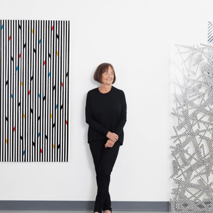 Artist Annalee Schorr poses in her studio, surrounded by her works on paper and acrylic and duct tape installations.