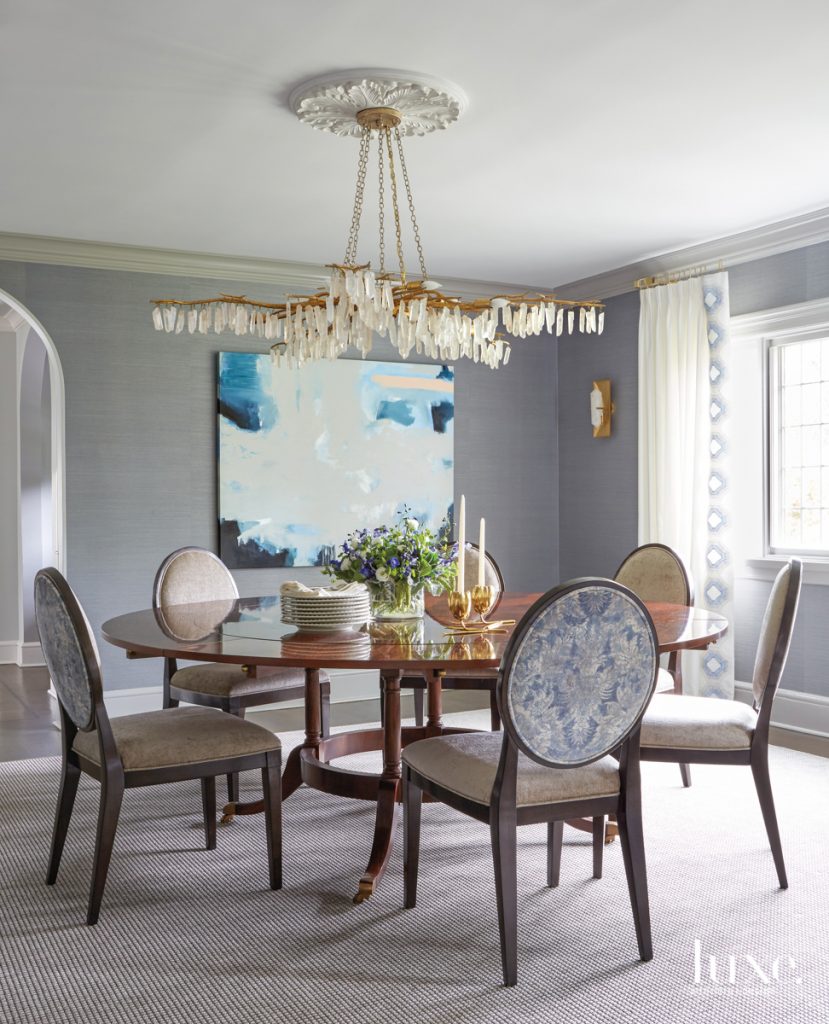 The dining room really reflects Jennifer," Alex says. An elegant Currey & Company chandelier hangs above an EJ Victor table, which is surrounded by Bernhardt chairs upholstered in JF Fabrics material on the inside and Cowtan & Tout on the backs. The painting is by Kelly Rossetti.