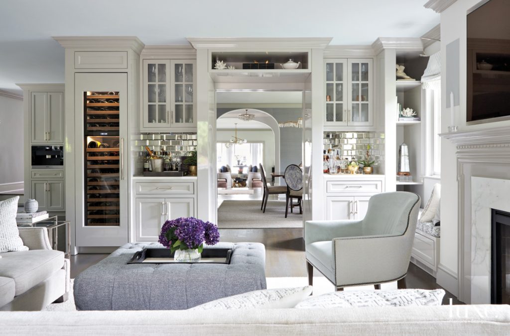 In the family room, millwork by Arte Wood Solutions sets off a cocktail area that encourages guests to linger. Or, one can simply recline with a book on the Vanguard Furniture chair in front of the custom ottoman swathed in David Sutherland fabric.