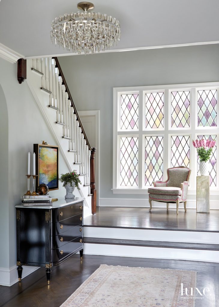 The homeowners were drawn to the original stained-glass window in the foyer of the home, as the husband's mother had been a stained-glass artist. "It was very close to their hearts," says designer Rajni Alex. A vintage animal-print chair plays off of the window's pastel tones, and a Visual Comfort chandelier adds a touch of glamour.