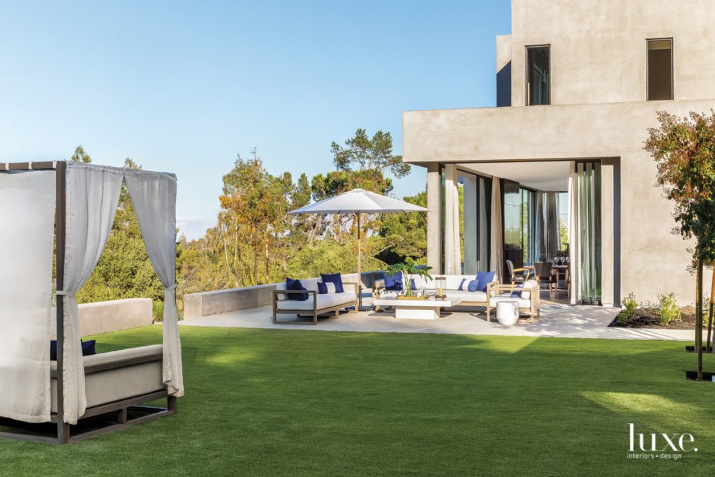 Entertaining often extends to the outside seating area located off the great room, where the doors by Euroline Steel Windows & Doors slide open to establish an easy indoor-outdoor flow. The teak sofas and side chair surround an ivory stone and concrete coffee table, all from RH.