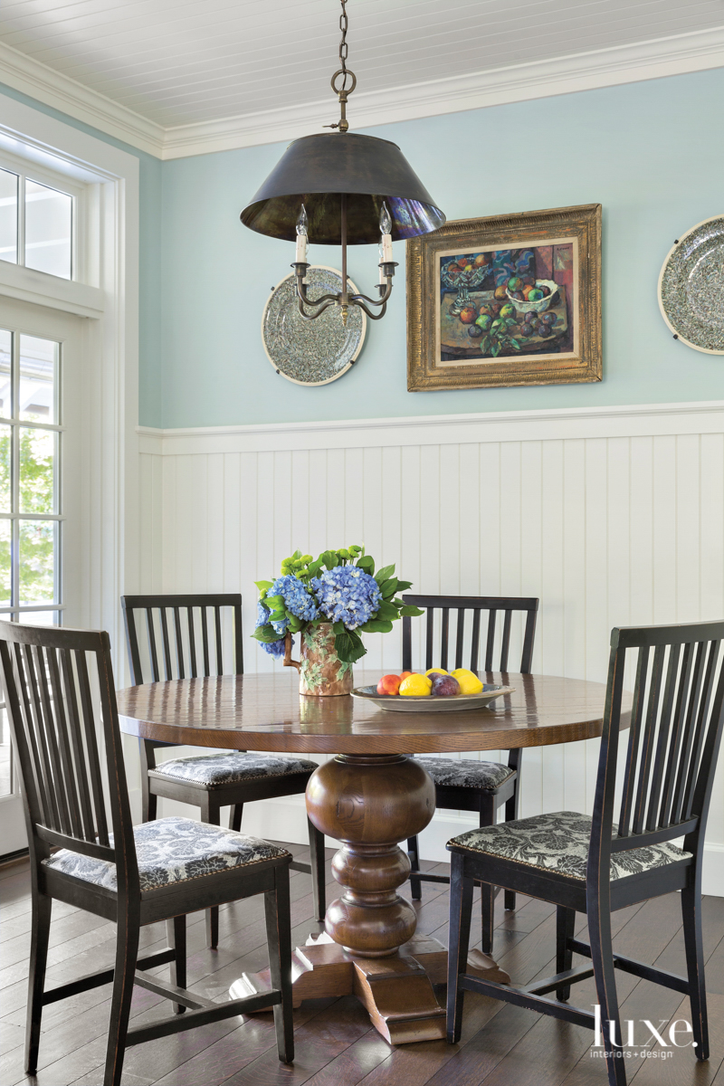 Farmhouse-style kitchen with beadboard paneling and round table in eating area