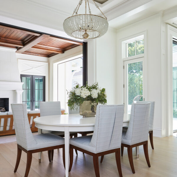A Breezy Lanai Makes It Easy To Embrace Year-Round Sunshine white oval dining room table with curry and company crystal chandelier