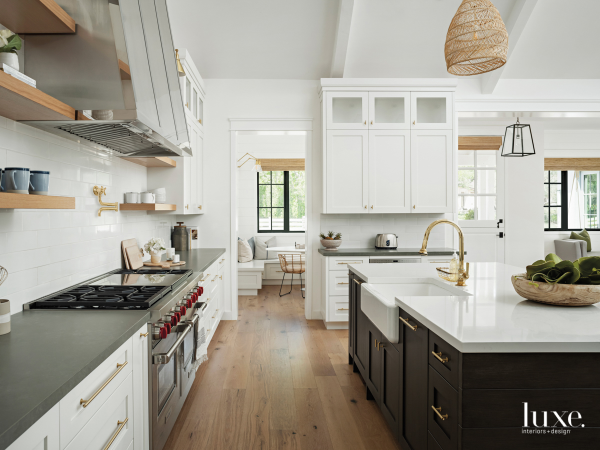 kitchen with a custom hood, island with white marble countertops and dark cabinetry