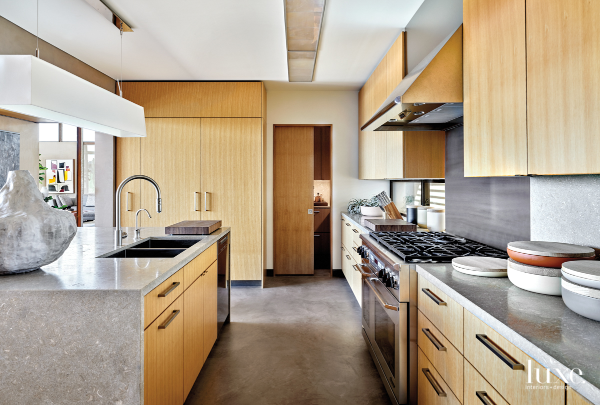 The kitchen that has clean lines, light wood and gray stone.
