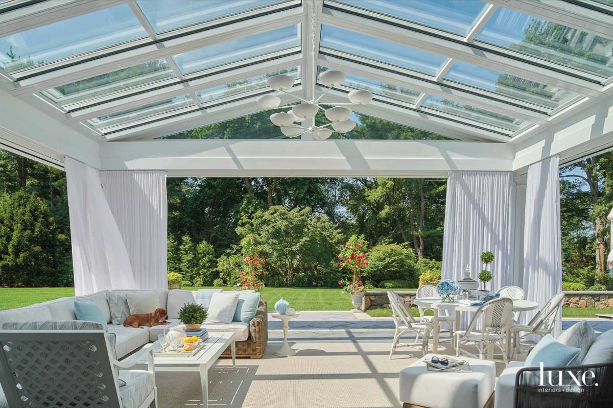 outdoor living space that is set in the gardens under a greenhouse with all-white furnishings