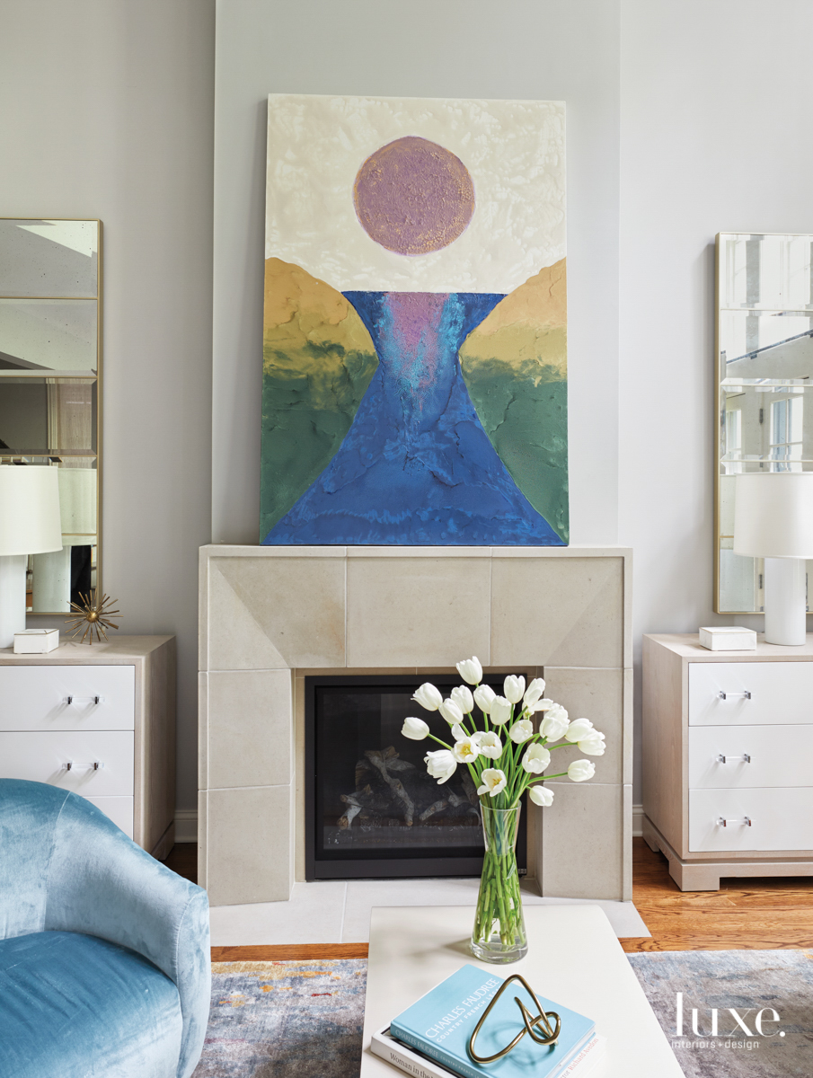 fireplace with art above it and blue arm chair with side tables