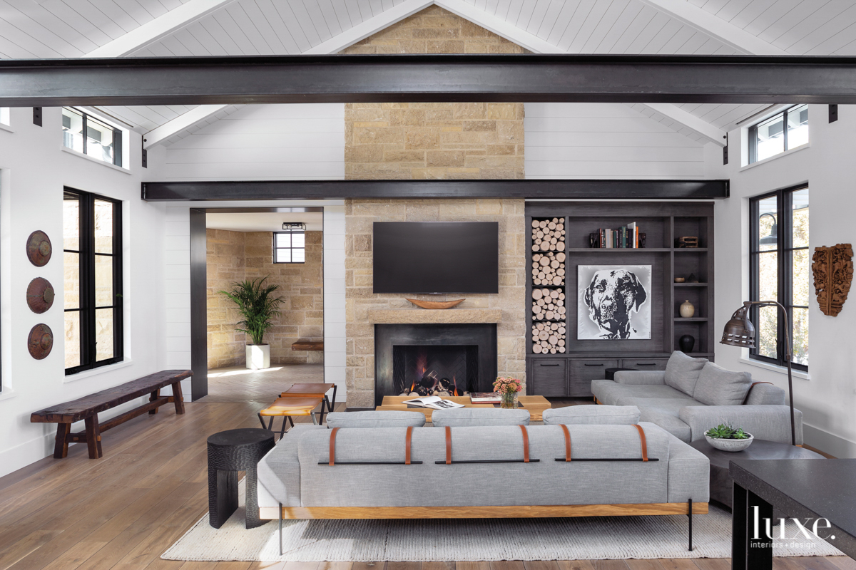 living room with tall fireplace, couch, and dark steel beans across the top