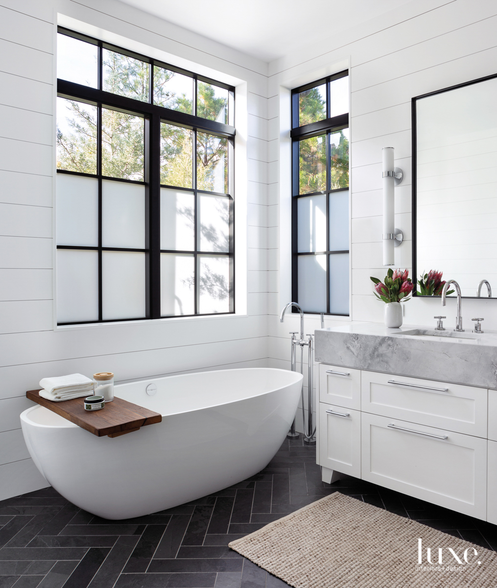 master bathroom with stand alone tub and white walls with white cabinetry