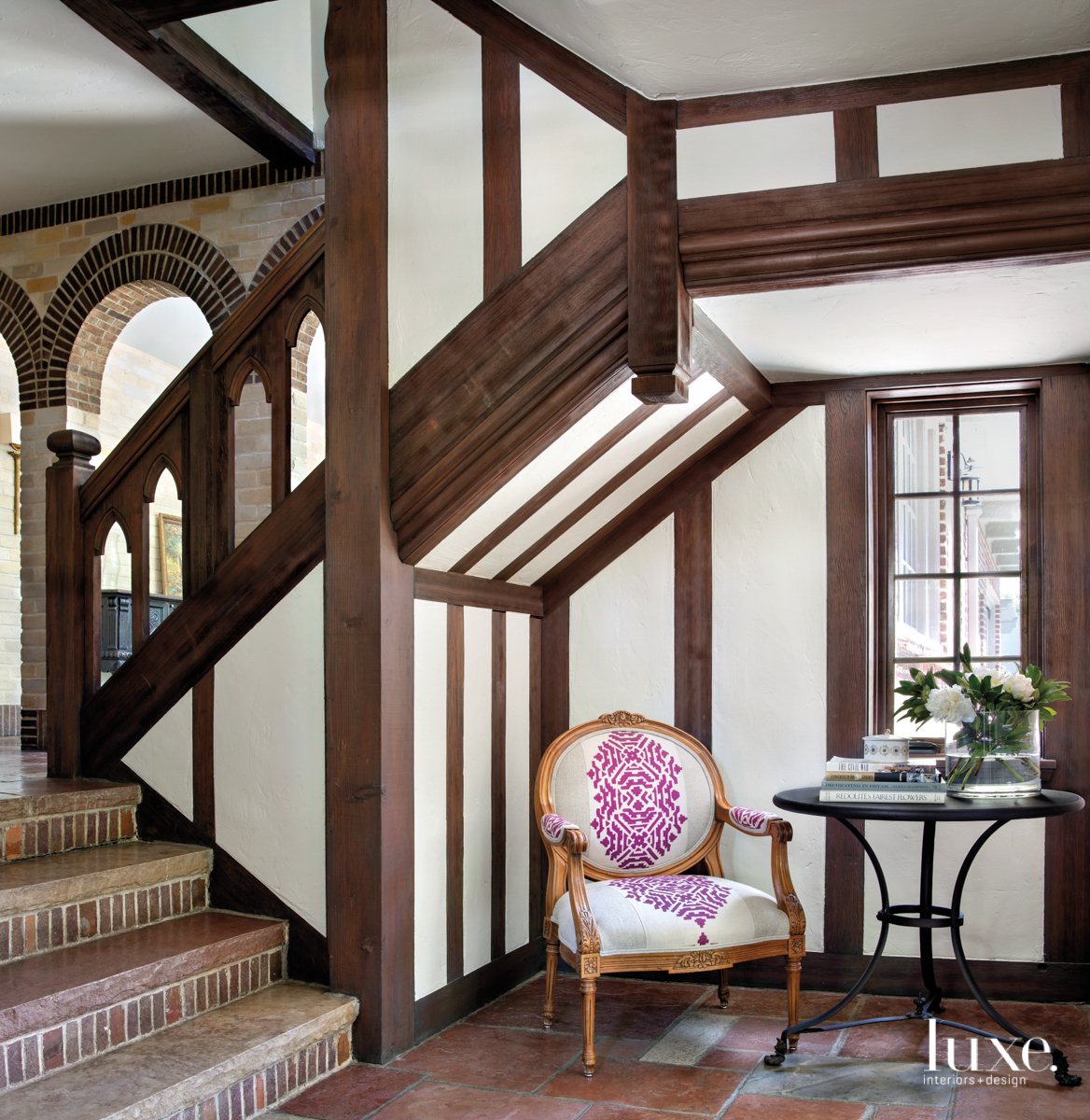 Entry with dark beams and accents. A chair with a hot-pink upholstery detail sits by a small table.