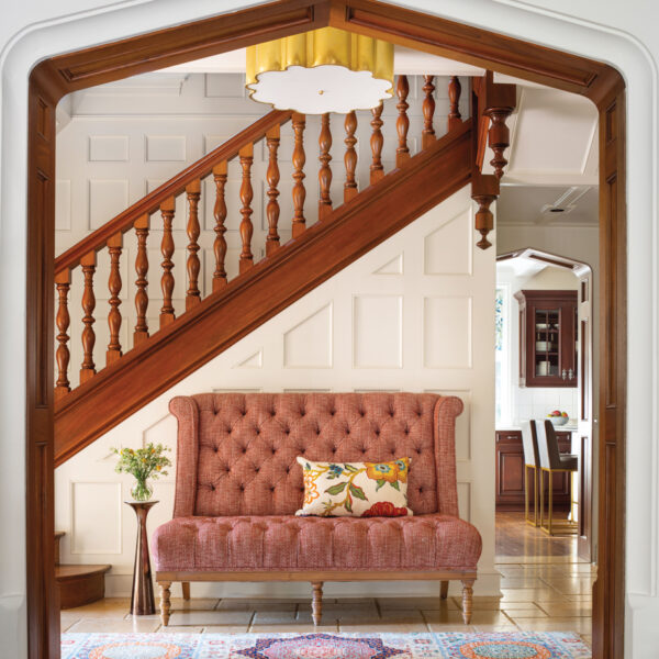 The Vibrant Denver Home With A Speakeasy Original To The 1928 Traditional Tudor The original stair rail shines in the new white interior. Beneath it is a rose-colored settee.