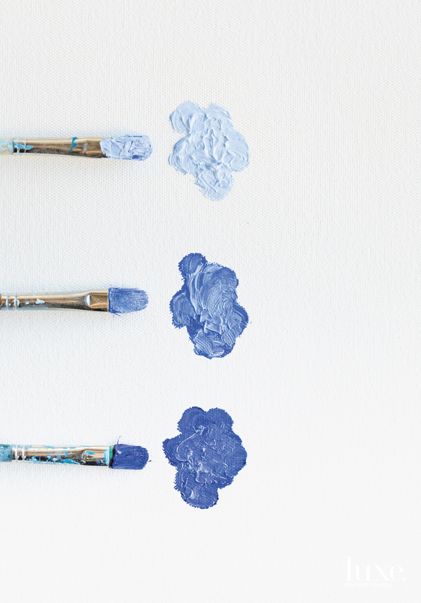 Paint brushes dipped in different shades of blue.