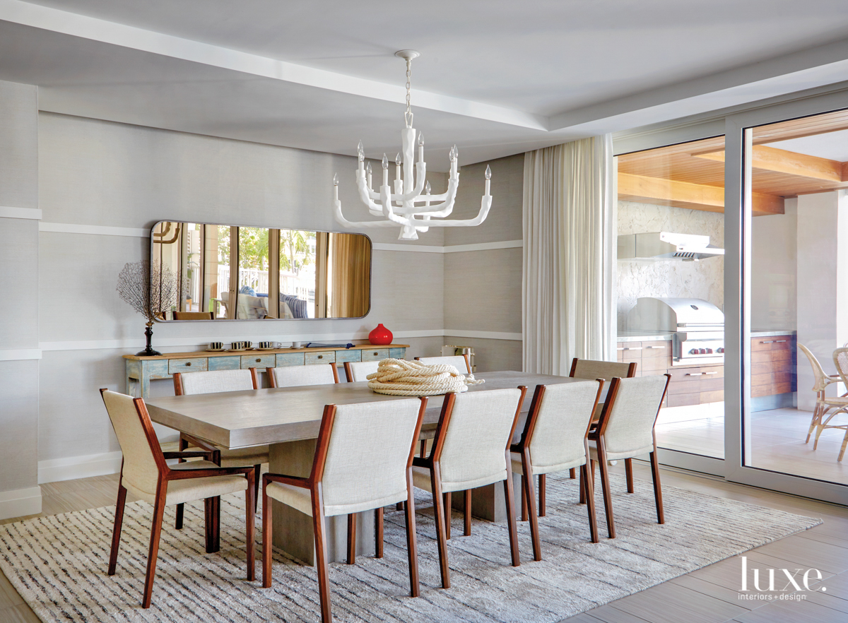 dining table with many cloth chairs, atop a wool rug with a mirror on the wall