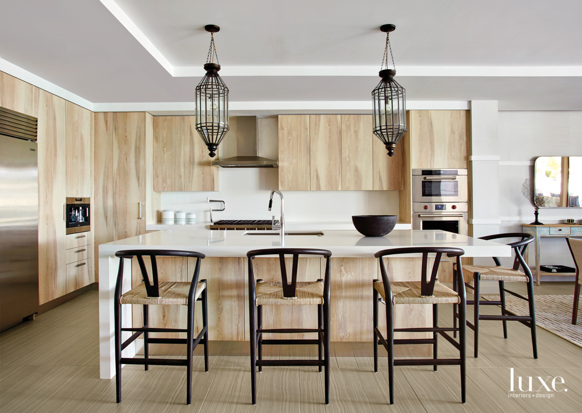 kitchen with wicker and brass barstools and wood cabinetry and hanging brass light fixtures