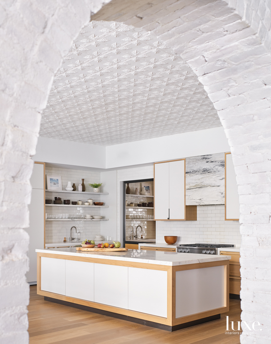 kitchen with textured ceiling, white back splash and island