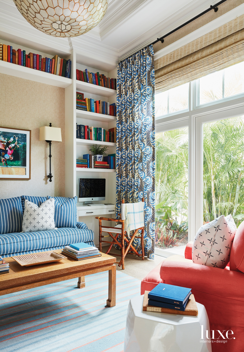 Den with blue draperies and sofa and red armchair