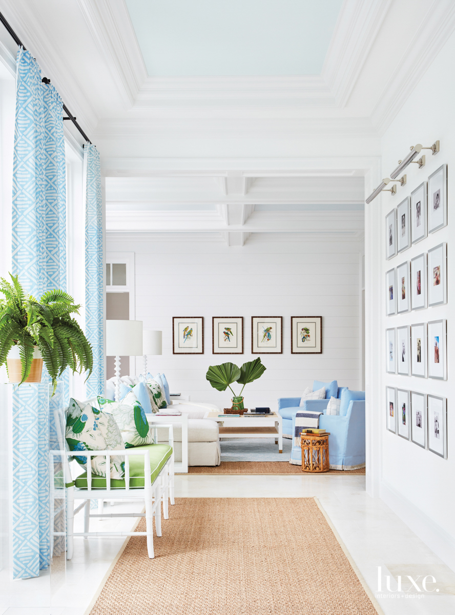 Living area with blue sofas, artwork and blue draperies