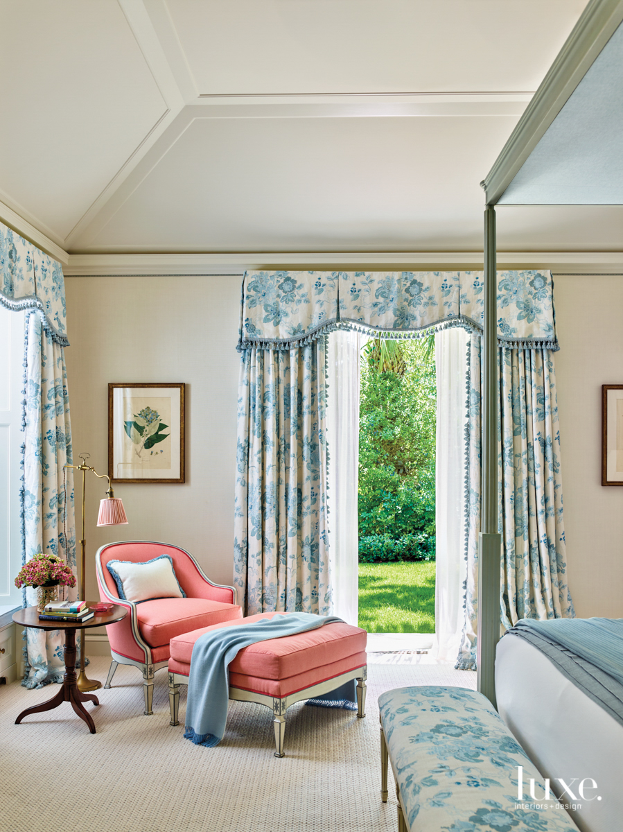 bedroom with blue and white patterned draperies and salmon armchair and ottoman