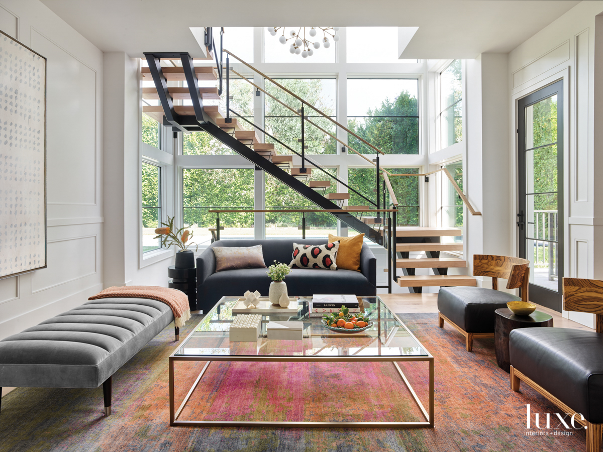 living room with staircase, pink and orange rug and floor to ceiling windows