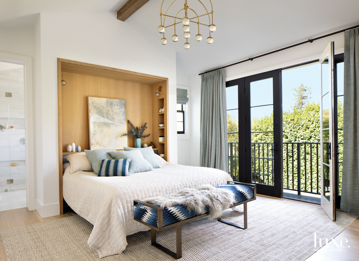 master bedroom with a patterned bronze bench and multi-arm light fixture