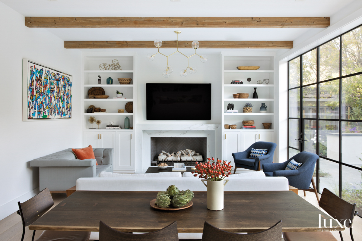 family room with wood beams and built-in bookshelves with a marble fireplace