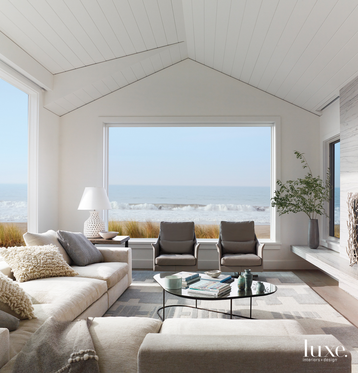 Crashing ocean waves sit right outside the window of this cream colored living room.