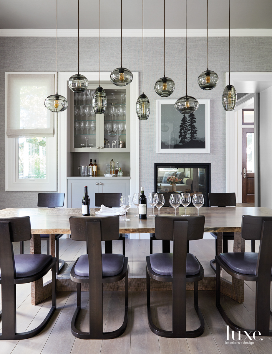 The dining room has a long table surrounded by chairs. A line of pendants hangs overhead.